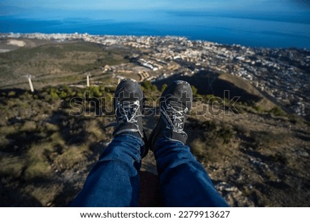 Man dangling his legs on top of Mount Calamorro with a beautiful view of the mountains and the city of Benalmádena, Spain Foto d'archivio © 