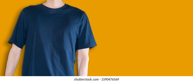 A Man In The Dark Blue T-shirt Mockup And Copy Space Against The Color Wall Backround, No Face