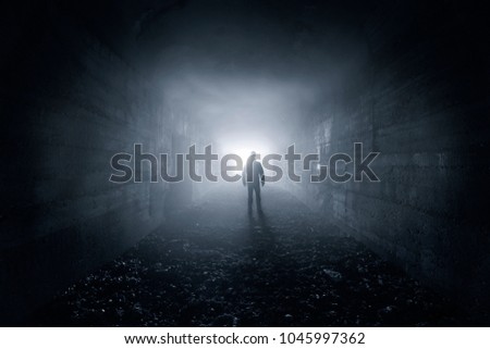 man in a dark concrete tunnel look out the exit - loneliness concept