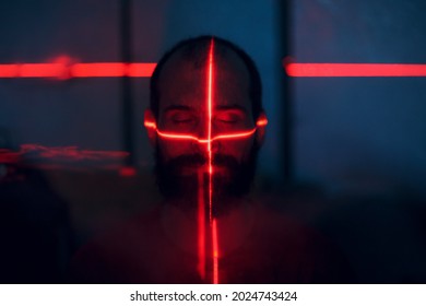 Man In Dark With Face Illuminated By Scan Red Laser On Contour.