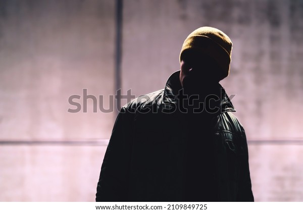 Man with dark face. Unknown stranger, stalker,\
thief or gangster in shadow. Secret hidden identity of mysterious\
person. Dangerous criminal in jacket. Handsome anonymous male\
fashion model in portrait