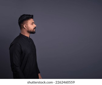 Man with dark hair with mustache and beard side profile portrait on gray background. Horizontal banner empty template gray copy space. Pakistani young man in traditional clothes