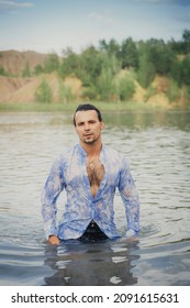 A Man With Dark Long Hair Emerges From The Water In A Wet Shirt.