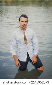 A Man With Dark Long Hair Emerges From The Water In A Wet Shirt.