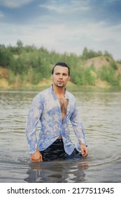 A Man With Dark Long Hair Emerges From The Water In A Wet Shirt