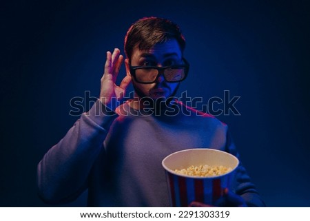 A man is in a dark room with neon lighting, watching a movie with 3D glasses and popcorn. High quality photo