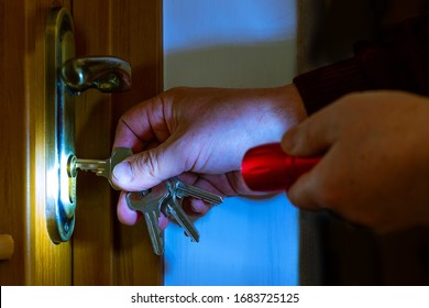 A man in a dark room shines a flashlight to open the door with a key