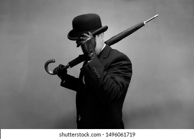 Man In Dark Suit And Leather Gloves Tipping Bowler Hat And Holding Umbrella Jauntily On Shoulder. Concept Of Classic And Eccentric British Gentleman Stereotype