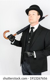 Man In Dark Suit And Leather Gloves With Umbrella On White Background. Concept Of Classic And Eccentric British Gentleman Stereotype. Retro Style And Vintage Fashion.