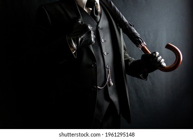 Man In Dark Suit And Leather Gloves Holding Umbrella On Black Background. Concept Of Classic And Eccentric British Gentleman Stereotype. Retro Style And Vintage Fashion.