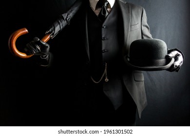 Retrato de un hombre con traje oscuro y guantes de cuero sosteniendo un paraguas y un sombrero Bowler. Concepto de Caballero Británico Clásico. Estilo retro y moda vintage.