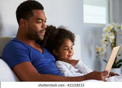 Man and daughter sitting in bed watching computer, waist up