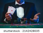 Man dealer or croupier shuffles poker cards show cards in a casino. Asain man holding two playing cards. Casino, poker, poker game concept