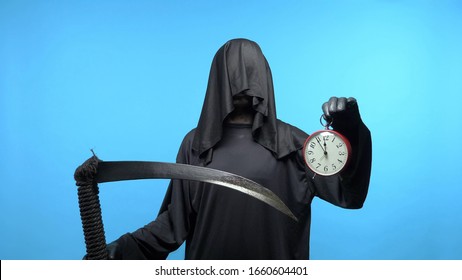 A man in a death suit with a scythe, shows a clock. blue background.