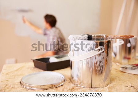 Man Decorating Room Using Paint Roller On Wall
