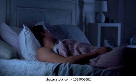 Man Deeply Sleeping On Bed In Dark Room, Comfortable Mattress And Pillows, Dream