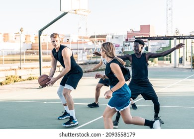 Man defending a ball while playing basketball with friends in an outdoor court - Powered by Shutterstock