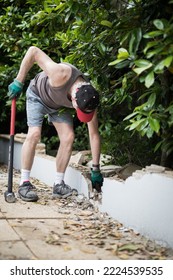 A Man Demolishing A Wall