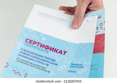 A man demonstrates Russian certificates of vaccination against coronavirus infection COVID-19. The hand holds the official state Russian vaccination documents. Cyrillic inscription CERTIFICATE