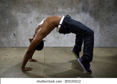 Man Demonstrating Core Balance Exercises Or Yoga On Urban Background. He Is Dressed In Hip Hop Style Clothing But Shirtless To Show Off Muscles.