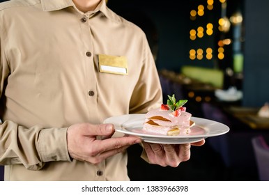 Man in denim shirt holding in hands white plate with pancakes seasoned by honey and blackberry. Minimalistic photo of cooking breakfast, dessert pancake in the hands of a waiter in a cafe - Powered by Shutterstock