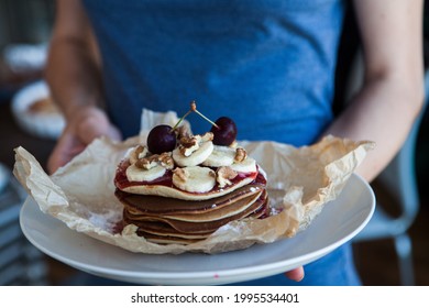 Man in denim shirt holding in hands white plate with pancakes seasoned by honey and blackberry. Minimalistic photo of cooking breakfast. - Powered by Shutterstock