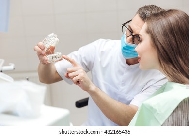 Man Dentist Show Dentures Teeth At Dental Surgery To His Patient At The Clinic