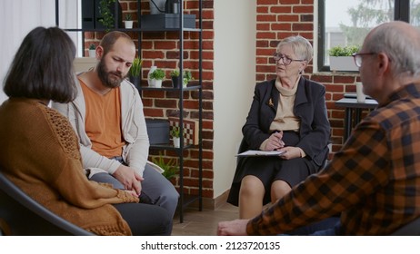 Man With Depression Making Confession At Aa Therapy Meeting With Alcoholics People. Person Telling Addiction Story To Receive Help And Advice From Therapist At Support Rehab Group.