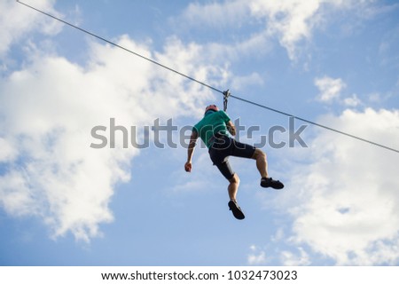 a man descends on a rope, a sport in an extreme park, A man walking along a zip line,