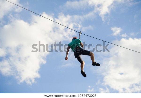 a man descends on a rope, a sport in an\
extreme park, A man walking along a zip\
line,