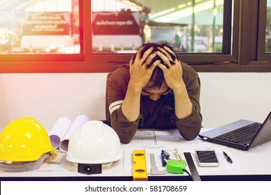 The Man Of Designer Sitting Stress With Work On The Table And Sunset Background