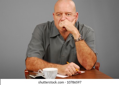 Man at desk with calculator and note paper looking serious or thoughtful - Shutterstock ID 10786597