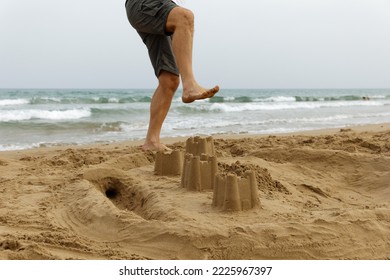 A man destroys sand castles by the sea