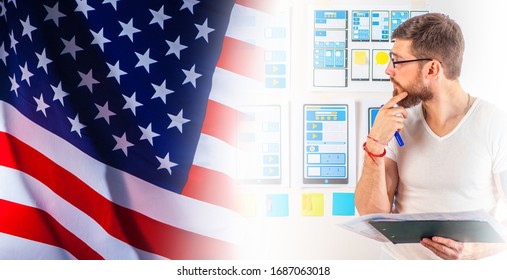 A man is developing a mobile app. Mobile app designer on the background of the American flag. A man is developing a website for an American company. Remote work. - Powered by Shutterstock