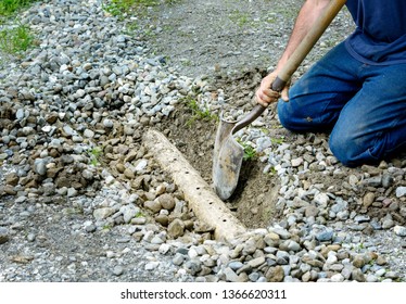 Man Digging Out French Drain In Driveway To Clean Out