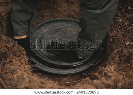Man digs up a discovered cache place in the forest in the form of a plastic barrel.