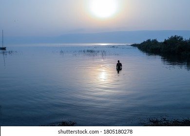 Man dipped in the water of Galilee Lake in Israel at sunrise. - Powered by Shutterstock