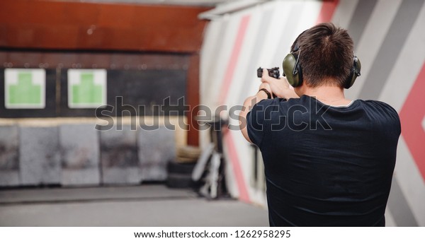 Man directs firearm gun pistol at target firing
range or shooting range.