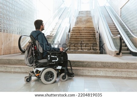 Man with disability on wheelchair stopped in front of staircase, raising awareness of architectural barriers and accessibility issues