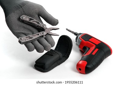 A Man Disassembles Folding Pliers. In The Background Is An Electric Screwdriver. Multi-tool. A Home Tool For Small Home Repairs.