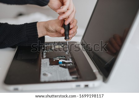 A man disassembles a laptop. Computer service and repair concept. Laptop disassembling in repair shop, close-up. Electronic development, electronic device fixing