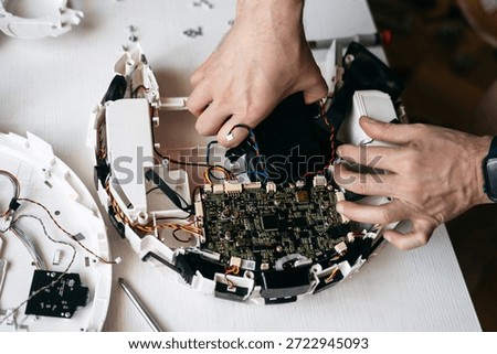 A man disassembles a vacuum cleaner and takes out the microcircuits. 