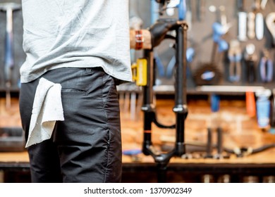 Man disassembling shock absorber of a bicycle fork at the workshop, close-up view - Shutterstock ID 1370902349