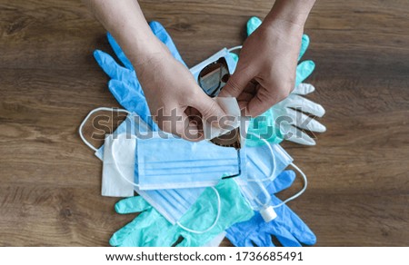 man disinfects glasses on the background of medical masks protection against COVID-19 on a wooden background close-up