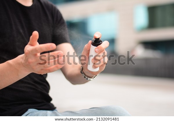 man disinfects his\
hands with a spray can