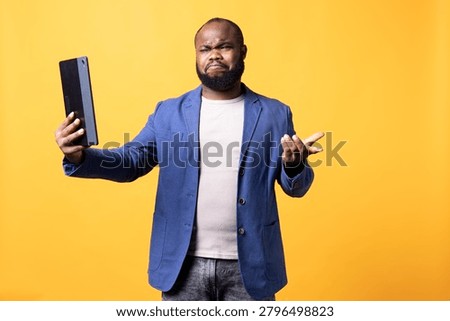Man dismayed by stupid things said by friend in video call, studio background during an online video call.