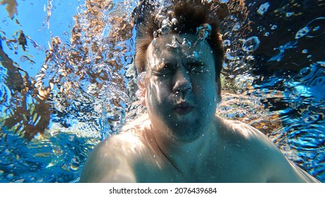 A Man Dives Into The Pool With A Camera In His Hands. Shooting Under Water. Camera For Extreme Recreation And Tourism.