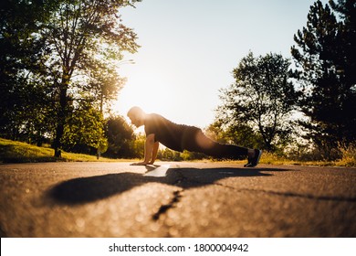 Man do push-ups at the street, Crossfit man and lifestyle concept. doing push ups on outdoors. background park. Young and fit man having evening workout outdoor. park sunset background. 
