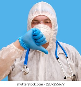 Man Doctor Medic In A Protective Suit Uniform With Goggles And Face Mask On A Studio Blue Background. Paramedic In White Antiviral Protective Clothing Wearing An N95 Respirator And Safety Glasses