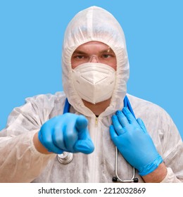 Man Doctor Medic In A Protective Suit Uniform With Goggles And Face Mask On A Studio Blue Background. Paramedic In White Antiviral Protective Clothing Wearing An N95 Respirator And Safety Glasses